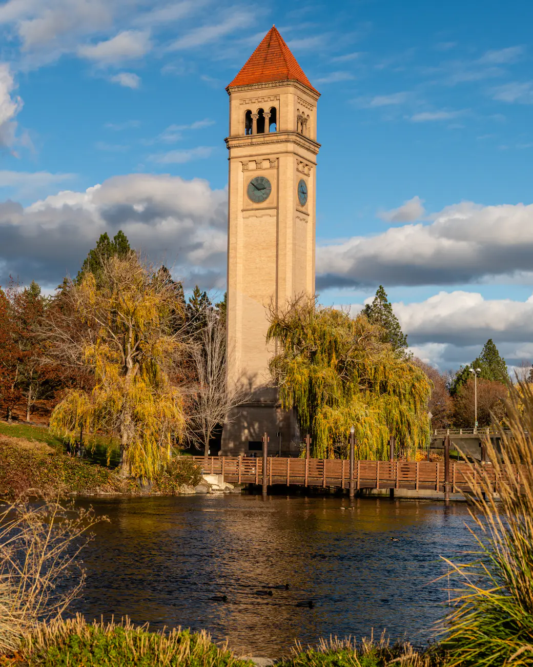 The clock tower in Riverfront Park above autumn willows and the footbridge over the Spokane River